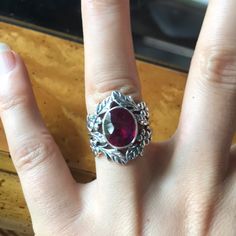 a woman's hand with a ring on it and a red stone in the middle