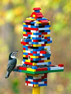 a bird is perched on top of a building made out of legos