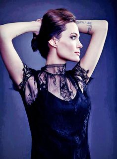 a woman with tattoos on her arm and neck posing for a photo wearing a black dress