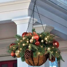 a hanging basket filled with christmas ornaments and pine cones on top of a door way