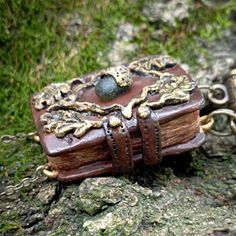 an old book with chains attached to it sitting on the ground next to some rocks