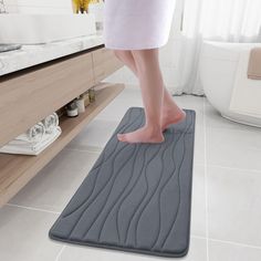 a person standing on a bathroom mat in front of a sink