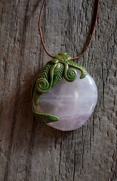 a white stone with green leaves on it sitting on a wooden table next to a cord