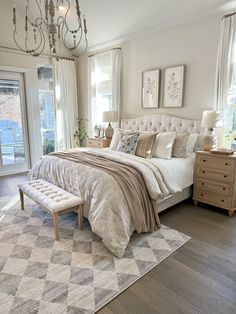 a bedroom with a large bed, chandelier and two windows in the room