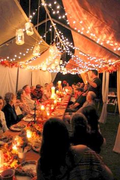 a group of people sitting around a table with food and candles in front of them