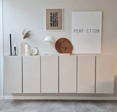 a white cabinet sitting in the middle of a room next to a lamp and pictures