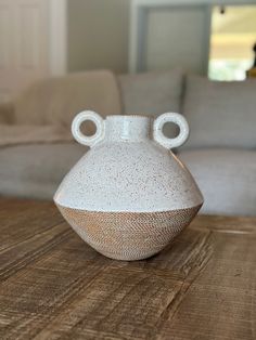 a white vase sitting on top of a wooden table