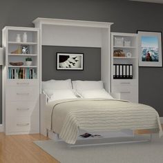 a white bed sitting in a bedroom next to a book shelf