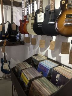 an assortment of guitars and records on display in a music store, with notes pinned to the wall