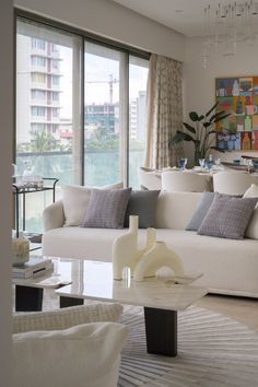 a living room filled with white furniture and large glass doors leading to an outside balcony