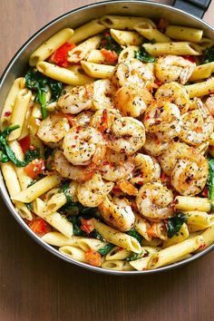 pasta with shrimp and spinach in a skillet on a wooden countertop, ready to be eaten