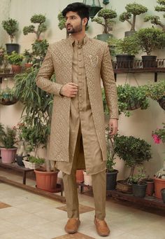 a man standing in front of potted plants wearing a tan colored sherwa