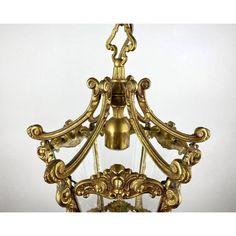 a golden chandelier hanging from the ceiling with a bell on it's side