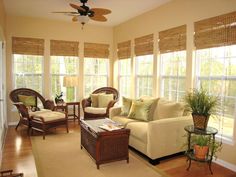 a living room filled with furniture and windows covered in shades of light colored wood blinds