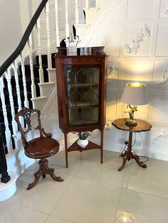 two chairs and a table sitting in front of a banister with a lamp on it