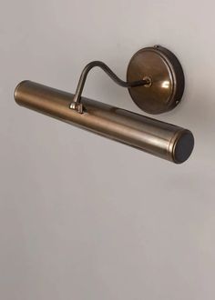 an antique brass toilet roll holder on a white wall with a black handle and round knob