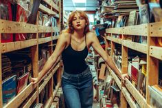 a woman is standing in the middle of a book shelf filled with books and cds