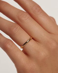 a woman's hand with a gold wedding ring on it, and the middle finger is