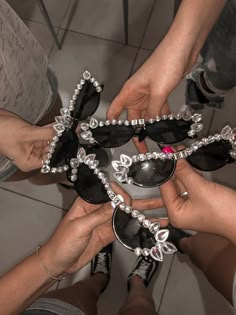 several people are holding up some black and white shoes with jewels on them, while one person holds onto the other's hand