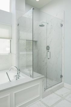 a white bathroom with a walk in shower next to a bathtub