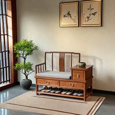 a wooden bench sitting next to a potted plant on top of a rug in front of a window