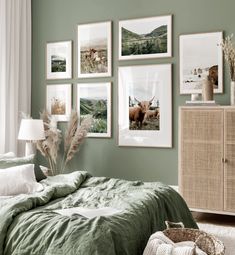 a bedroom with green walls and pictures on the wall above the bed, along with a wicker dresser