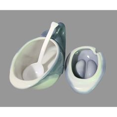 two bowls with spoons in them sitting next to each other on a gray background