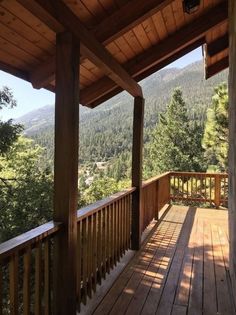 a wooden porch with railings and trees in the background