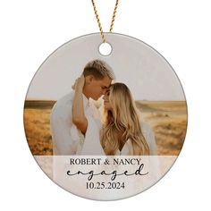 a round ornament with an image of a couple kissing and the words engaged printed on it