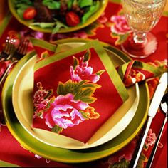 the table is set with red and green place mats, silverware, and napkins