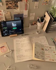 an open book sitting on top of a desk next to headphones and other items