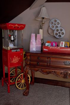 an old fashioned popcorn machine sitting on top of a wooden dresser next to a lamp