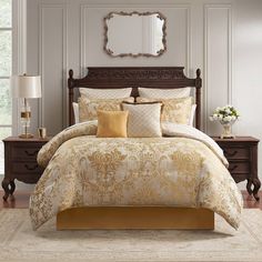 a bed with yellow and white comforters in a bedroom next to a dresser, mirror and lamp