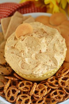 a plate with pretzels, crackers and dip in it on the side