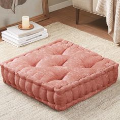 a pink square footstool sitting on top of a rug