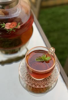 a cup of tea sitting on top of a glass saucer next to a jar