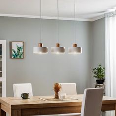 a dining room table with four lights hanging over it