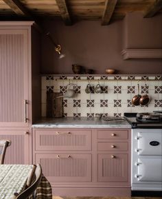 a kitchen with pink cabinets and an oven in the center, along with a dining room table