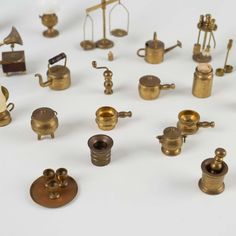 an assortment of miniature brass objects on a white surface, including tea kettles and other items