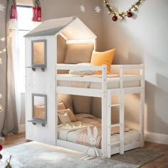 a white bunk bed with a little house on the top and pillows in front of it