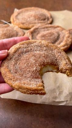 a hand holding a sugared donut on top of wax paper