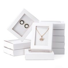 three white boxes with two necklaces and one earring in them on a white background