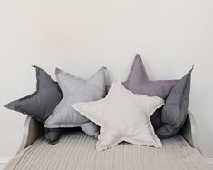 three star shaped pillows sitting on top of a bed in front of a white wall