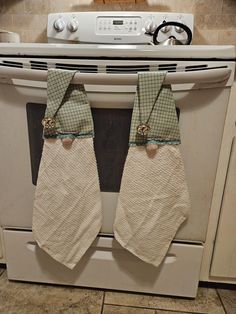 two oven mitts hanging from the front of an oven