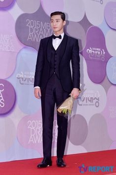 a young man in a tuxedo and bow tie standing on a red carpet