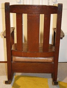 an old wooden chair sitting on top of a yellow rug in front of a white wall