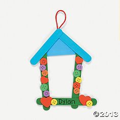 an ornament shaped like a house with buttons hanging from it's side