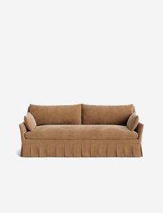 a tan couch sitting on top of a white wall