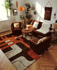 a living room filled with lots of furniture and plants on top of a hard wood floor