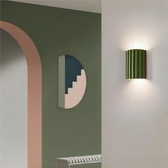 a green and pink wall with two lamps on it's sides next to a white radiator